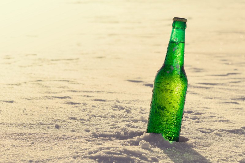 Bottle of cold beer on the snow. Close up view.